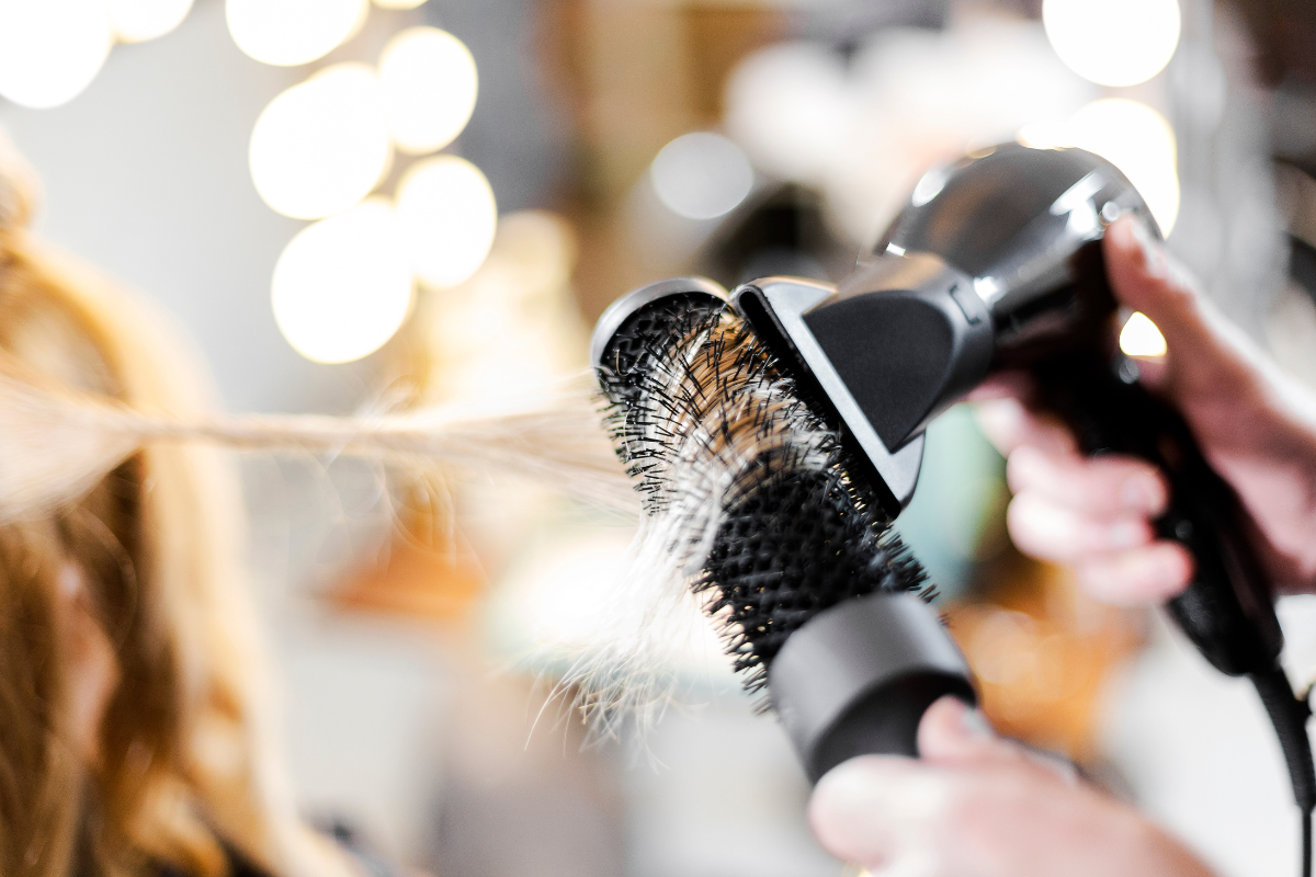 Secador de cabelo pequeno e dobrável sobre uma bancada ao lado de uma nécessaire.