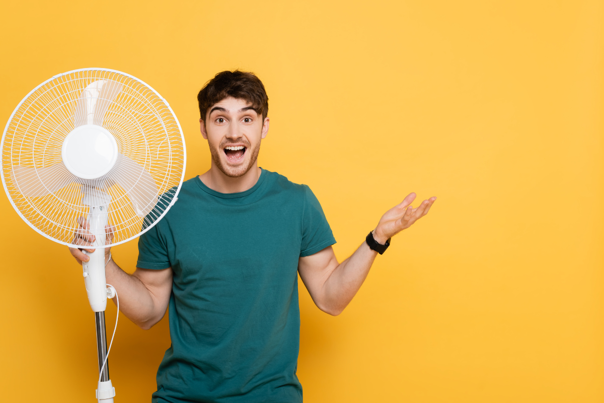 Ventilador de torre compacto preto em uma mesa ao lado de um sofá.